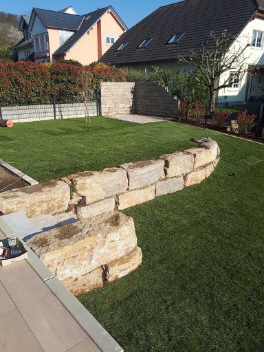 Garten mit Natursteinmauer als Sitzmauer und Rasenfläche