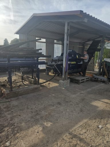 Mitarbeiter bedient Holzspaltmaschine unter Dach