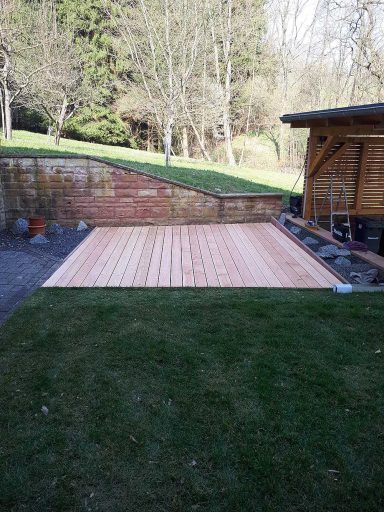 Holzterrasse mit angrenzendem Rasen im Garten